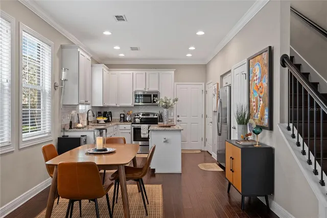 a kitchen with stainless steel appliances a dining table chairs and a refrigerator