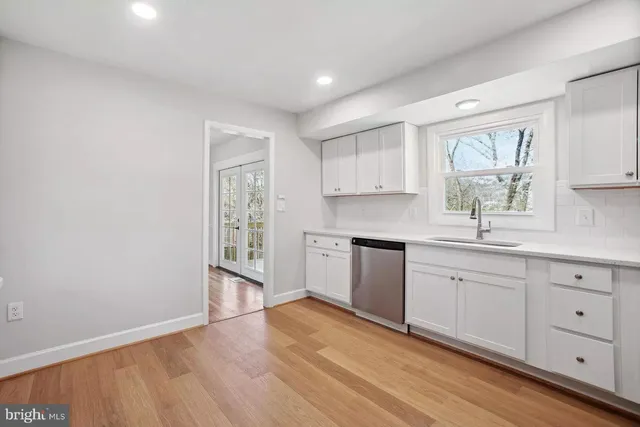 a kitchen with granite countertop a stove a sink and white cabinets with wooden floor
