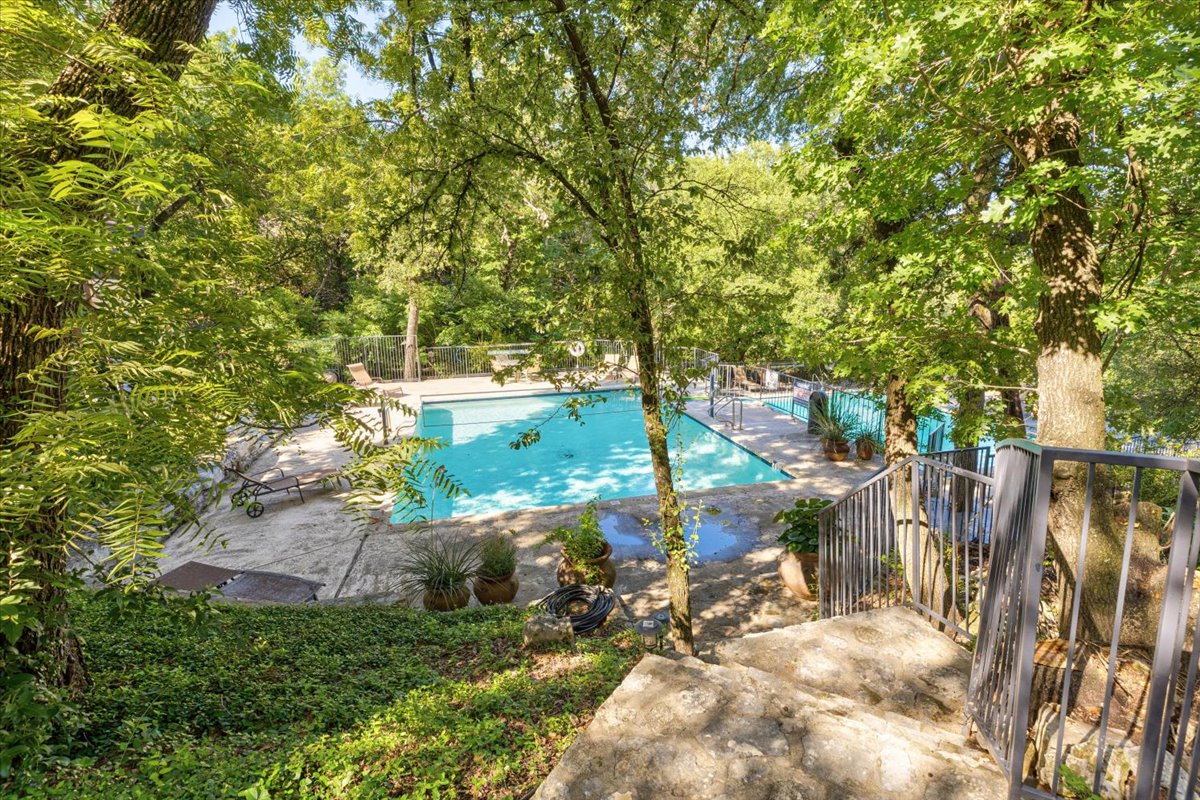 4711 Spicewood Springs Road, Unit 4222 Austin, TX 78759 - Photo 28 of 35 A tranquil community pool area is framed by lush, mature trees, offering a private outdoor retreat.