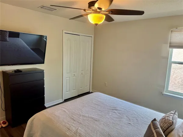 a bedroom with a bed and a flat tv screen on dresser