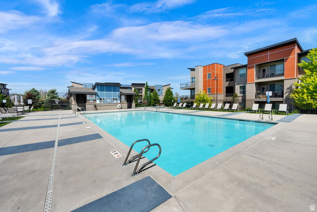 7713 Navarro View Court Midvale, UT 84047 - Photo 27 of 41 Outdoor swimming pool with concrete decking, surrounded by multiple modern residential buildings featuring balconies