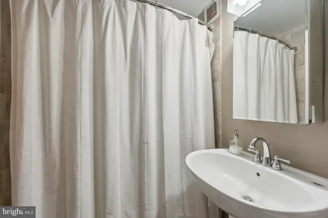 a bathroom with a sink a mirror and shower curtain