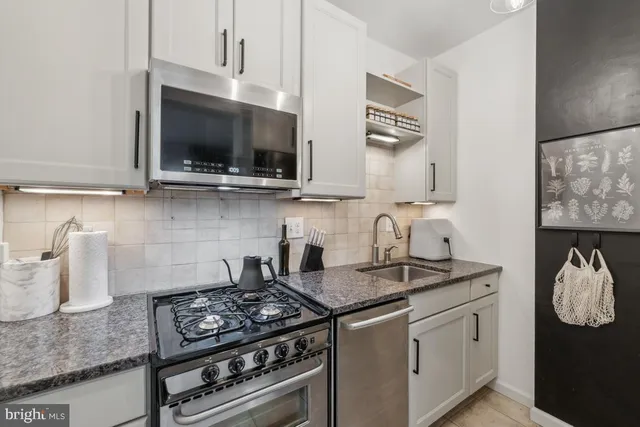 a kitchen with stainless steel appliances granite countertop a sink stove and microwave