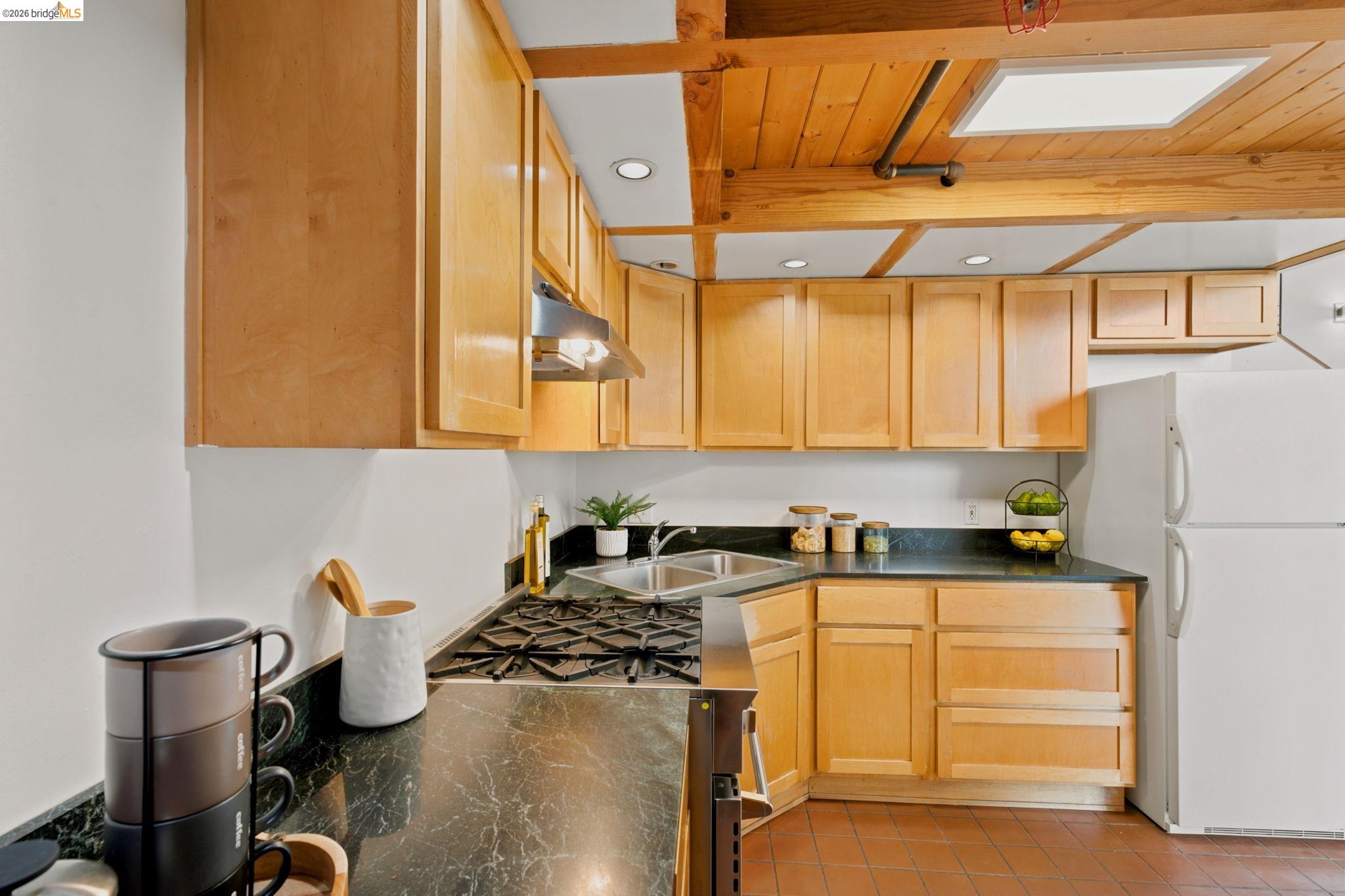 1920 Union Street, Unit 9 Oakland, CA 94607 - Photo 16 of 35 Kitchen featuring light wood cabinetry, dark countertops, a stainless steel sink, a gas range, and a built-in refrigerator