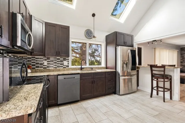 a kitchen with stainless steel appliances granite countertop a refrigerator and a stove top oven