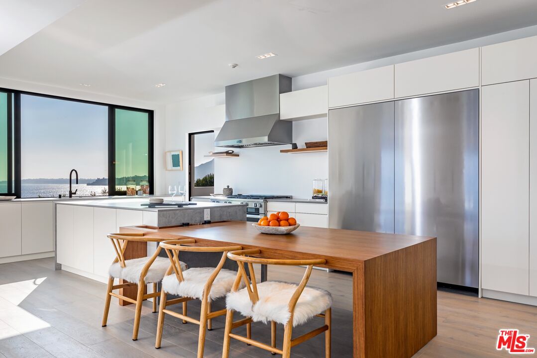 25225 Malibu Road Malibu, CA 90265 - Photo 11 of 23 a kitchen with stainless steel appliances a dining table chairs and sink