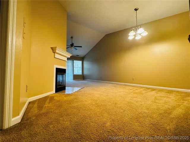 en empty room with a ceiling fan and a fireplace