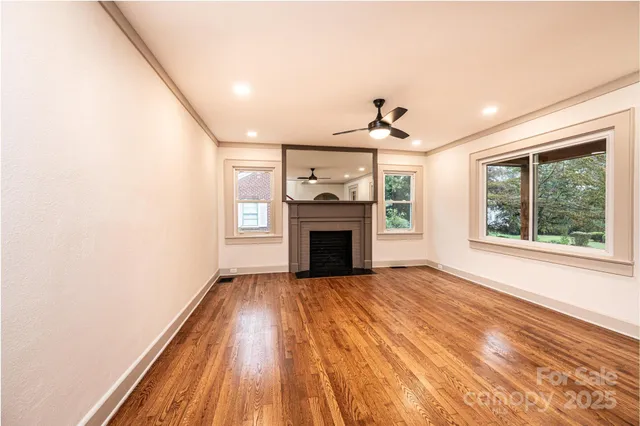 a view of a livingroom with a fireplace wooden floor and windows