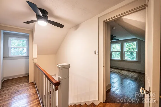 a view of empty room with wooden floor and fan