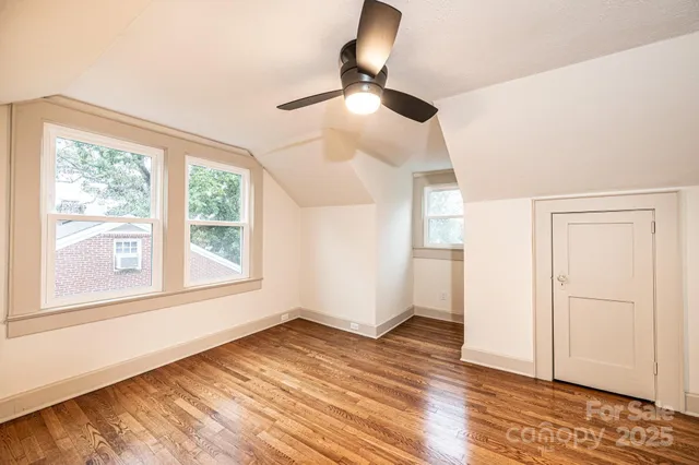 an empty room with wooden floor closet and windows