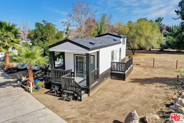 a view of a house with a wooden bench in a backyard
