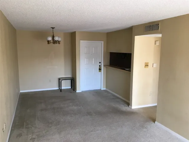 a view of a livingroom with a kitchen space and a refrigerator
