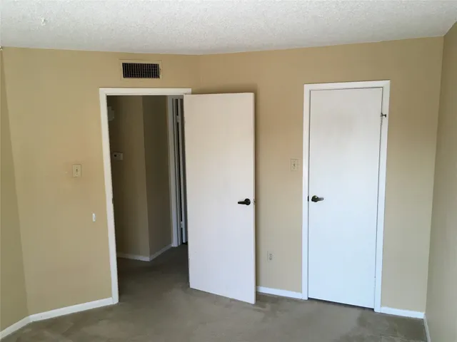 a view of an empty room with closet and wooden floor
