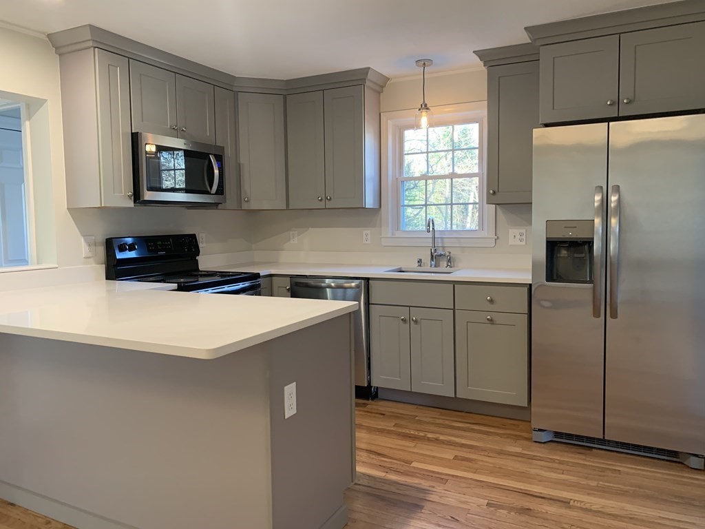7 Oregon Road Ashland, MA 01721 - Photo 4 of 27 a kitchen with a sink a microwave a refrigerator and cabinets