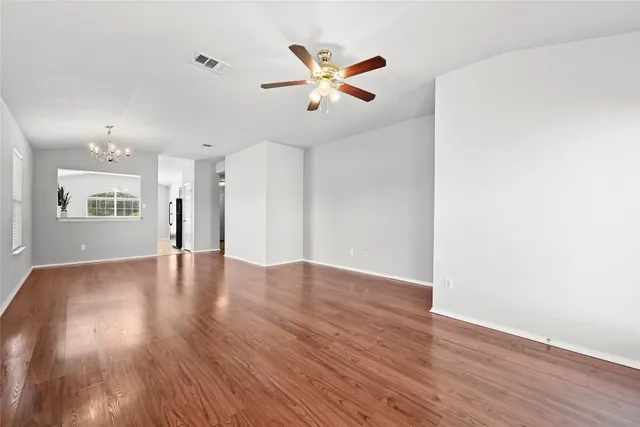 a view of empty room with wooden floor and ceiling fan