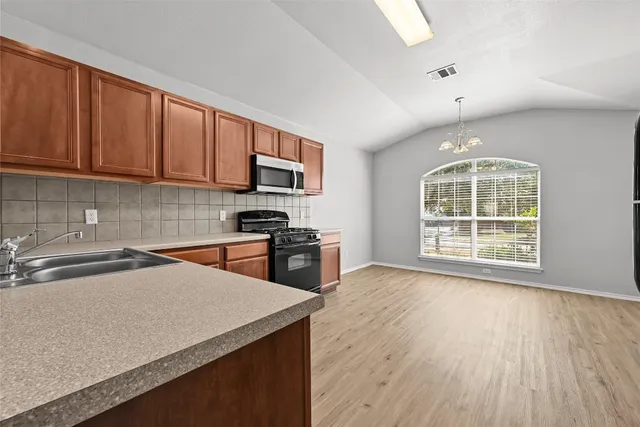 a large kitchen with stainless steel appliances granite countertop a stove a sink dishwasher and a refrigerator