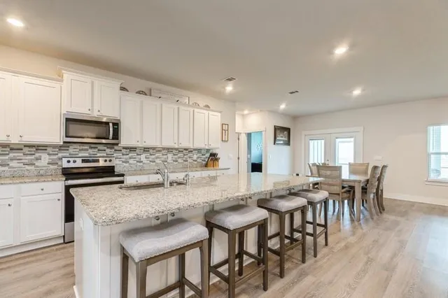 a kitchen with granite countertop kitchen island white cabinets and stainless steel appliances