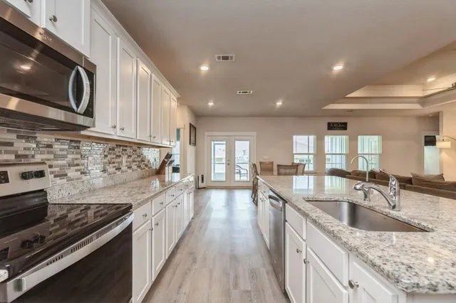 a kitchen with stainless steel appliances granite countertop a sink stove and cabinets