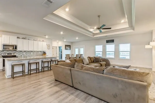 a living room with furniture kitchen and a wooden floor