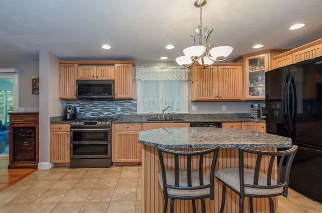 a kitchen with stainless steel appliances granite countertop a stove a refrigerator a oven a sink with a dining table and chairs