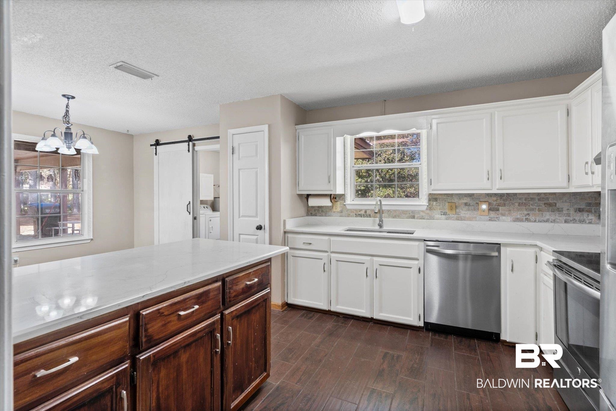180 Creax Road Axis, AL 36505 - Photo 7 of 35 Kitchen featuring white cabinetry, a barn door, a chandelier, stainless steel appliances, and a textured ceiling