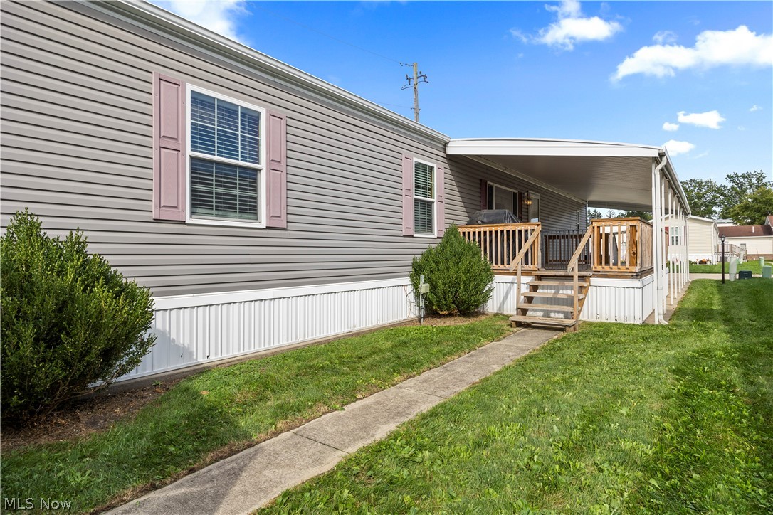 35157 Center Ridge Road, Unit 92 North Ridgeville, OH 44039 - Photo 35 of 40 Gray siding exterior with white trim, covered porch with wooden railing, concrete walkway, and established shrubbery