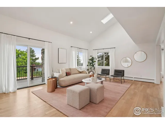 a living room with furniture a large window and wooden floor