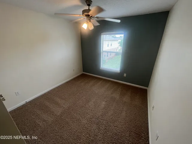 an empty room with a bathroom and a fan