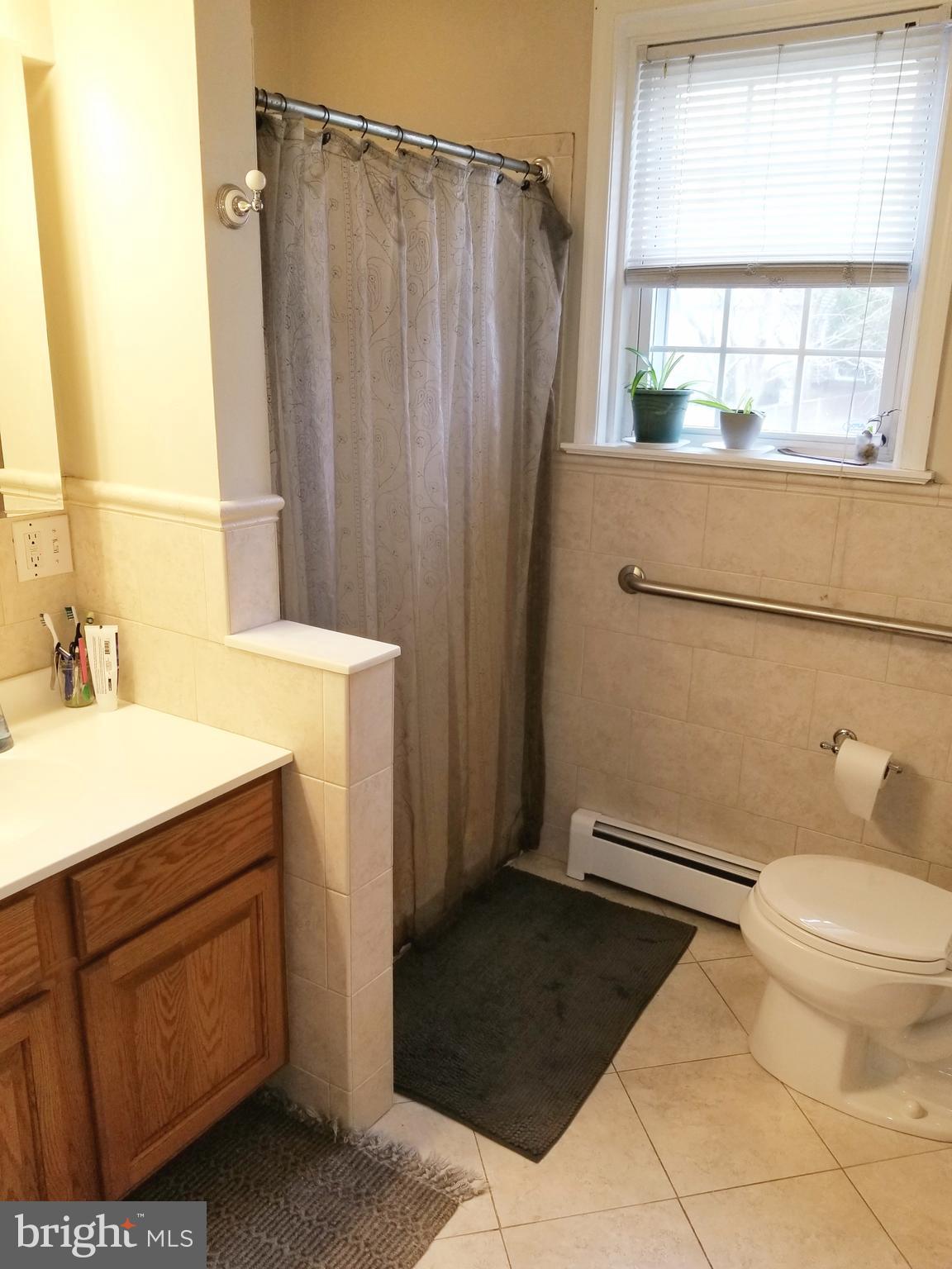 211 Ridley Drive Wallingford, PA 19086 - Photo 7 of 12 a bathroom with a sink a toilet a window and shower