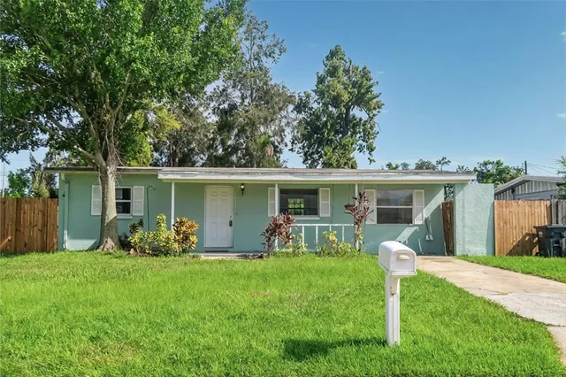 a backyard of a house with table and chairs plants and large tree