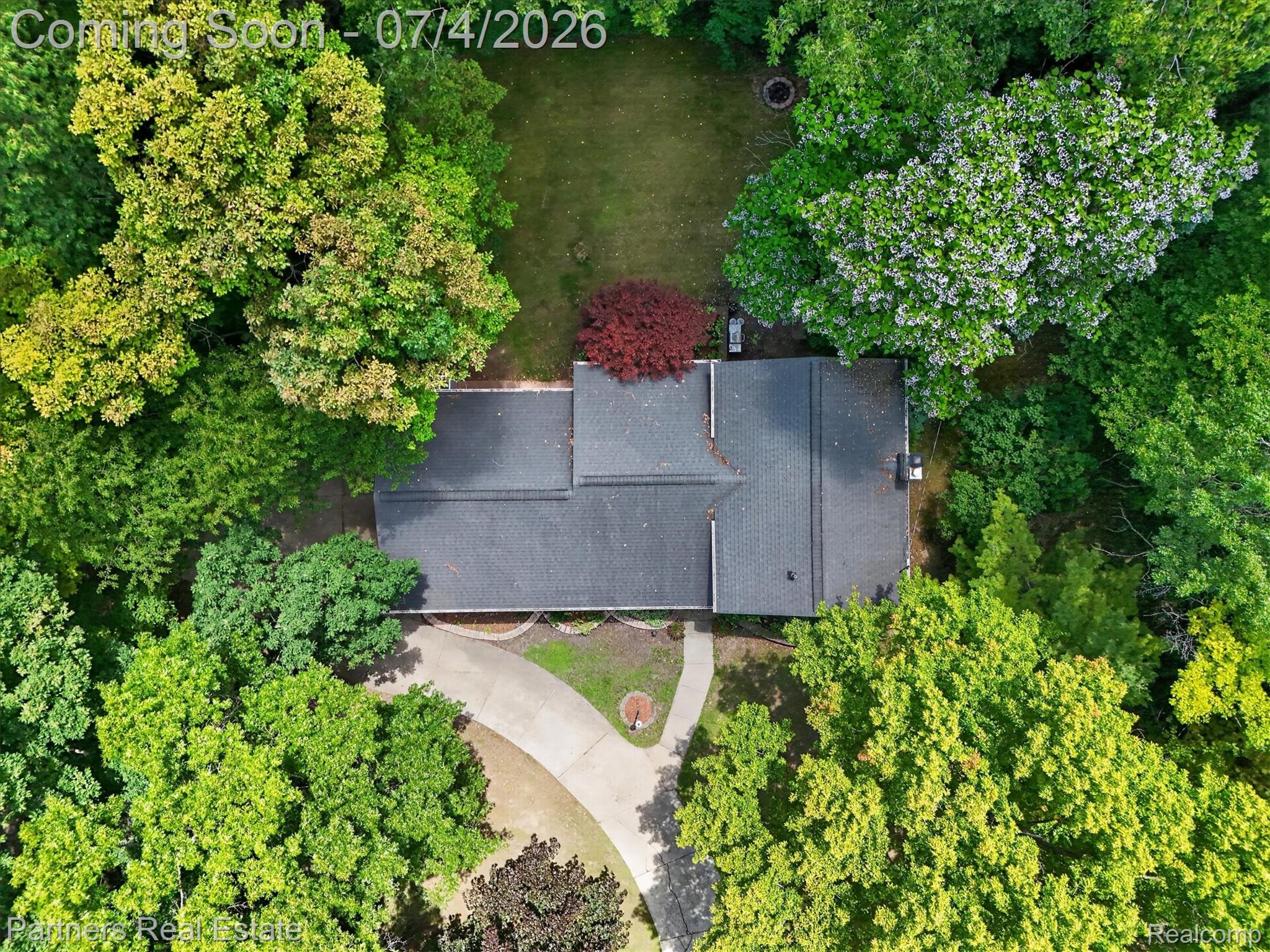 2500 Hubert Road Brighton, MI 48114 - Photo 48 of 53 Property surrounded by mature trees, featuring a dark shingle roof and a concrete driveway