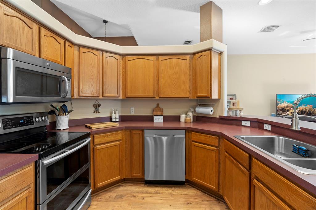 6480 Fall Street St. Cloud, FL 34771 - Photo 15 of 47 a kitchen with stainless steel appliances a stove sink microwave and cabinets