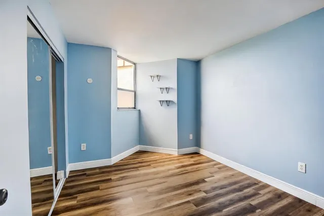 wooden floor in an empty room with a chandelier fan
