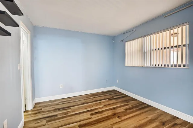 a view of a room with a large window and wooden floor