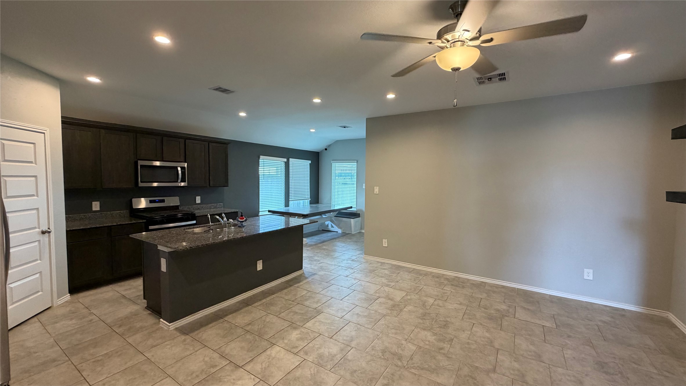 7518 Cynomys Court Rosharon, TX 77583 - Photo 14 of 21 a kitchen with kitchen island granite countertop a refrigerator a sink a stove a microwave and island with wooden cabinets