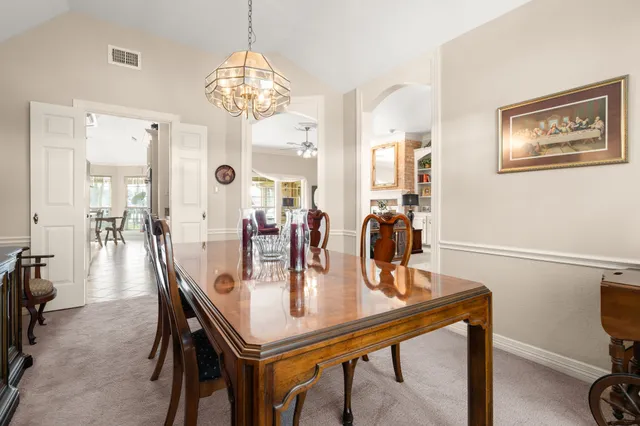 a dining room with wooden floor a chandelier a wooden table and chairs