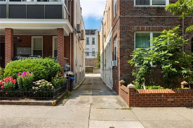 a view of a pathway that has potted plants and brick walls