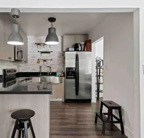 a kitchen with stainless steel appliances granite countertop a refrigerator a sink a stove and a wooden floors