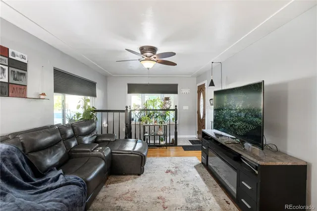 a living room with furniture a flat screen tv and floor to ceiling window
