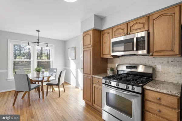 a kitchen with stainless steel appliances granite countertop a stove a microwave a dining table and chairs