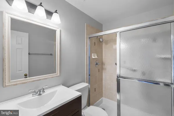 a bathroom with a shower sink vanity mirror and toilet
