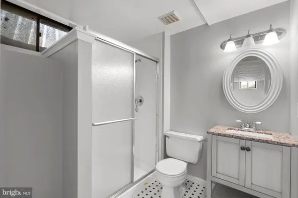 a bathroom with a granite countertop sink mirror vanity and toilet
