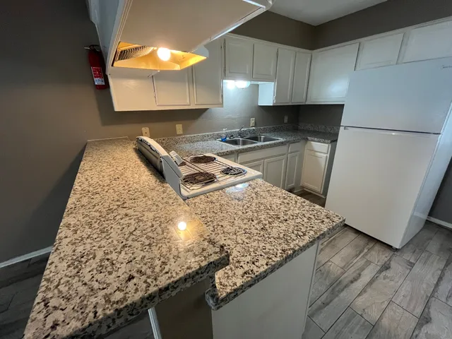a kitchen with granite countertop a sink a stove and a refrigerator