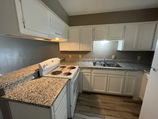 a kitchen with granite countertop a sink stove and cabinets