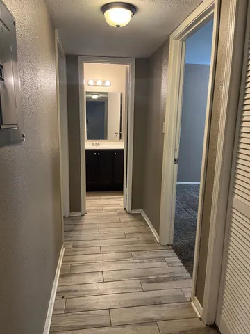 a view of a hallway with wooden floor and cabinet