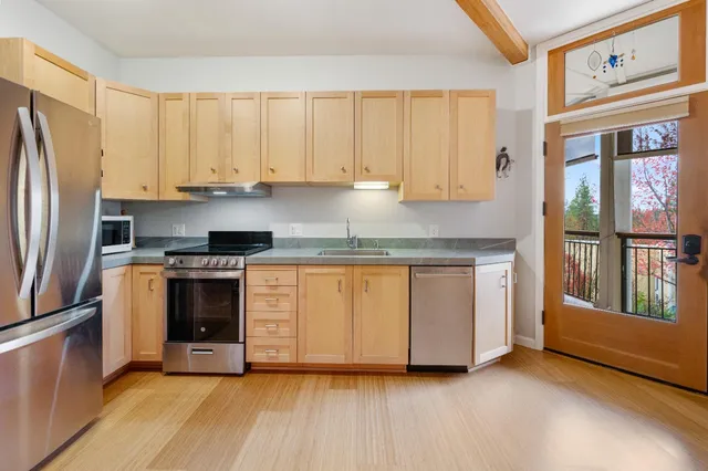 a kitchen with granite countertop a stove a sink and a refrigerator