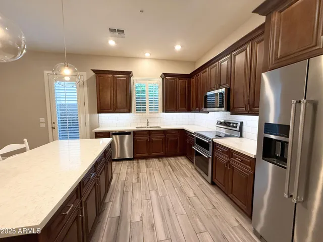 a large kitchen with stainless steel appliances kitchen island granite countertop a refrigerator a stove top oven a sink and dishwasher