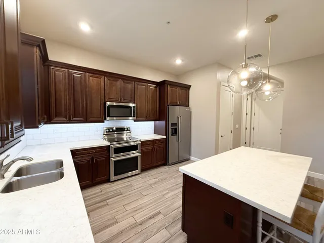 a kitchen with kitchen island a counter space a sink appliances and cabinets