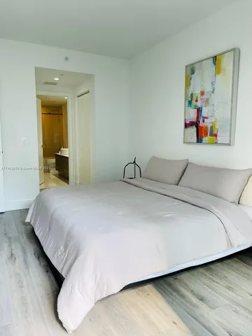 a bedroom with a bed and painting on the wall