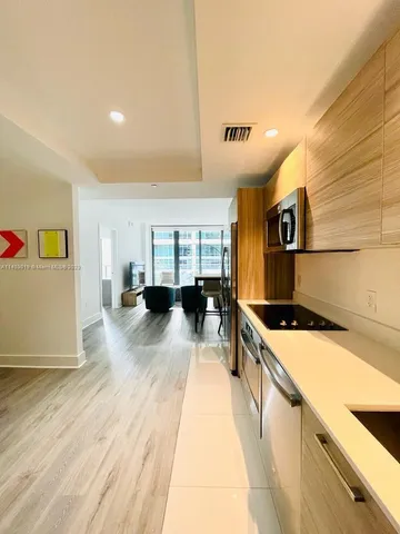 a living room with stainless steel appliances wooden floor and a rug